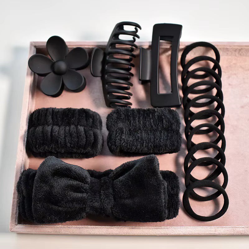 Set of black hair accessories including clips, flowers, and bands on a wooden tray.